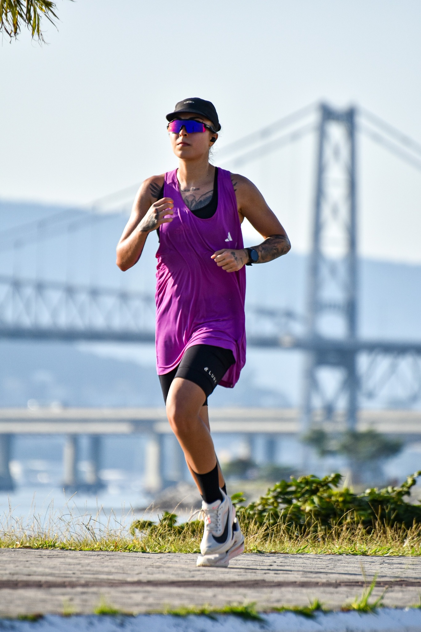 Mafê em treino de corrida com uma ponte ao fundo